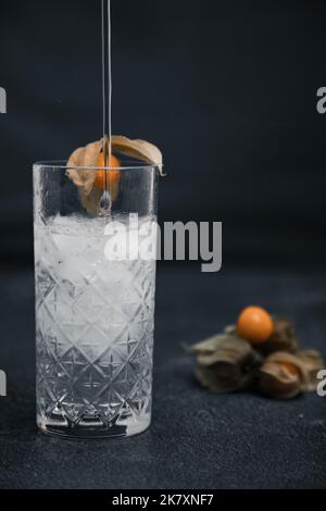 Cocktail mit Physalis alkekengi im Hintergrund gegossen und garnieren Stockfoto