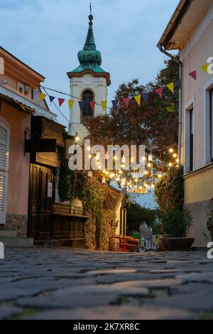 Stadtplatz mit schönen Stadtlichtern in Szentendre Hungary neben Budapest mit farbenfrohen Bannerleuchtendekorationen Stockfoto