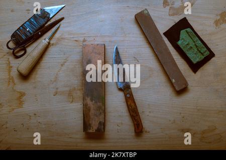 Altes rostiges Messer und Werkzeuge. Goya Pasta und Schleifstein. Messer und Griff mit Klebeband. Alte Handwerkzeuge. Stockfoto