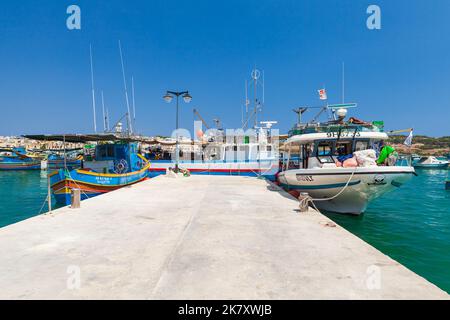 Marsaxlokk, Malta - 28. August 2019: Bunte Fischerboote werden an einem sonnigen Tag am Hafen von Marsaxlokk festgemacht Stockfoto