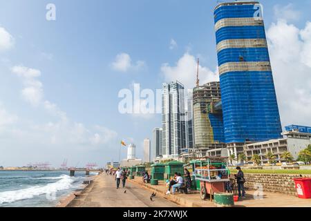 Colombo, Sri Lanka - 3. Dezember 2021: Colombo Downtown, Küstenansicht. Die Menschen laufen auf der Strandpromenade, moderne Wolkenkratzer und Hafenkrane stehen auf dem Wasser Stockfoto