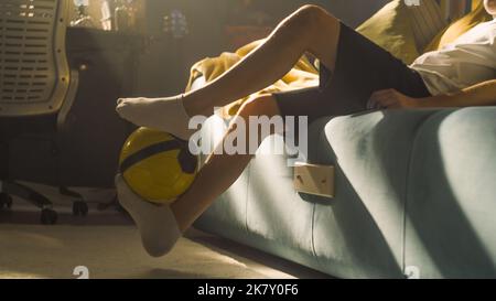 Junge Nahaufnahme Füße Bewegung tritt den Fußball in seinem Schlafzimmer. Führt Tricks mit dem Ball durch. Soccerr, Sport, Hobbys, Sportler cocept. Stockfoto