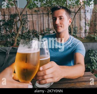 Lustig betrunkener Mann klirren frisch gebraute leichte Biergläser in einer Bar oder Kneipe oder einem deutschen Biergarten Stockfoto