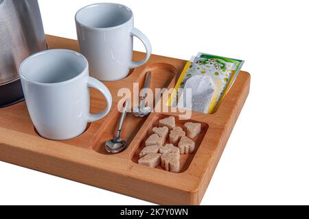 Eine Gruppe von Kaffeemaschinen in einem Hotelzimmer mit Edelstahl-Wasserkocher, sauberer Tasse, Teelöffel. Tee- und Kaffeetassen im Hotelzimmer, Keramikbecher Stockfoto