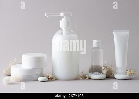 Komposition mit kosmetischen Hautpflegeprodukten, Steinen und Blumen auf Grau. Nahaufnahme, Kopierbereich Stockfoto