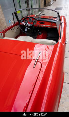 Ein klassischer Alfa Romeo 'Rosso Corsa' Spider Giula wartet auf den Eintritt zur Oldtimer- und Fahrradshow im Stadtzentrum von Sarlat-la-Caneda Stockfoto