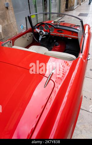 Ein klassischer Alfa Romeo 'Rosso Corsa' Spider Giula wartet auf den Eintritt zur Oldtimer- und Fahrradshow im Stadtzentrum von Sarlat-la-Caneda Stockfoto