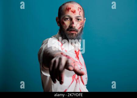 Portrait of halloween Zombie posiert vor der Kamera, sieht gruselig und gefährlich mit apokalyptischen Narben und blutigen Wunden im Studio. Böse aggressive Gehirn fressen Monster, erschreckende Leiche. Stockfoto