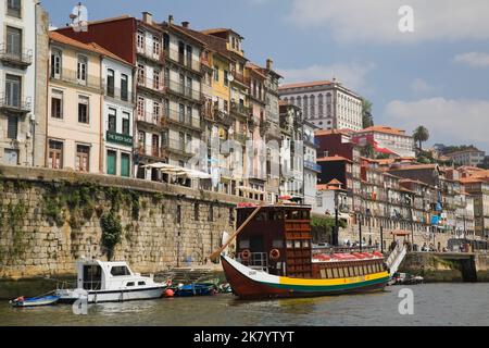 Geschäfte und Wohnhäuser in der Altstadt von Porto mit Blick auf den Fluss Douro mit Sightseeing-Boot, Portugal. Stockfoto