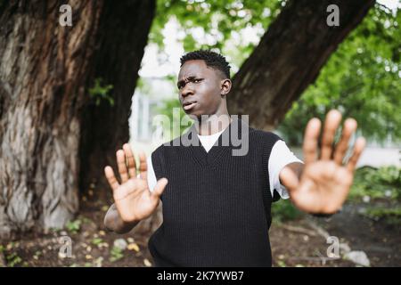 Schockiert junge 20s Afrikaner tragen lässige Streetwear im Park im Freien, dabei Stop-Not-Me-Schild mit Handflächen. Denial-Geste und Gesichtsausdruck. Herbst- oder Frühjahrssaison Stockfoto