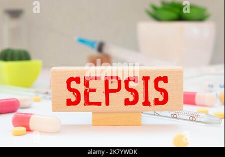 Ampulle und ein Holzblock mit der TEXTSEPSIS. Medizinisches Konzept Stockfoto