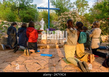 Junge Menschen knien und beten am Blauen Kreuz in Medjugorje, Bosnien und Herzegowina. Stockfoto