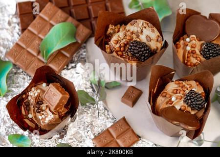 Schokoladen-Cupcake mit Brombeeren- und Eukalyptusblättern auf Silberfolie. Schokoladendessert. Verschiedene süße Tische. Süßigkeiten und Desserts. Backwaren Stockfoto