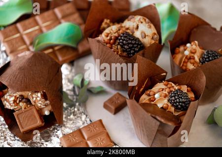 cupcake mit Brombeeren- und Eukalyptusblättern auf Silberfolie. Schokoladendessert. Verschiedene süße Tische. Süßigkeiten und Desserts. Backwaren Stockfoto