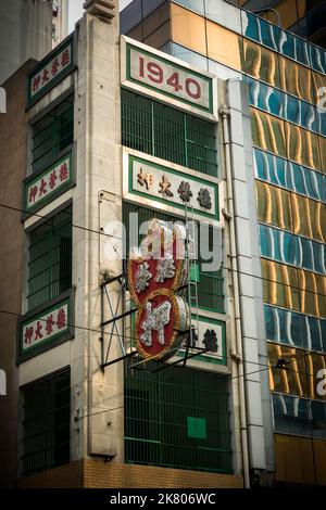 Außenansicht des Tak Wing Pawn Shop, eines traditionellen chinesischen Pfandladens in einem „tong lau“-Shophaus neben einem modernen Hochhausgebäude, Central, Hon Stockfoto