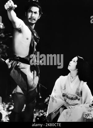 Toshiro Mifune & Machiko Kyo Film: Rashomon, In The Woods (1950) Charaktere: Tajomaru, Masako Kanazawa Regie: Akira Kurosawa 25. August 1950 **WARNUNG** Dieses Foto ist nur für redaktionelle Verwendung bestimmt und unterliegt dem Copyright von RKO und/oder des Fotografen, der von der Film- oder Produktionsfirma beauftragt wurde, und kann nur durch Publikationen im Zusammenhang mit der Bewerbung des oben genannten Films reproduziert werden. Eine obligatorische Gutschrift an RKO ist erforderlich. Der Fotograf sollte auch bei Bekanntwerden des Fotos gutgeschrieben werden. Ohne schriftliche Genehmigung der Film Company kann keine kommerzielle Nutzung gewährt werden. Stockfoto