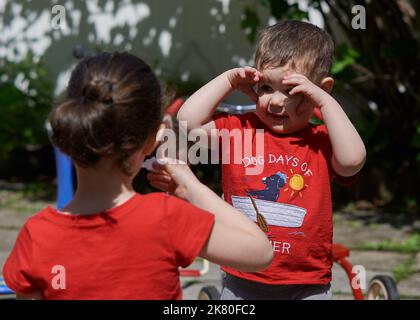 Geschwister spielen an einem sonnigen Tag im Hinterhof mit Seifenblasen Stockfoto