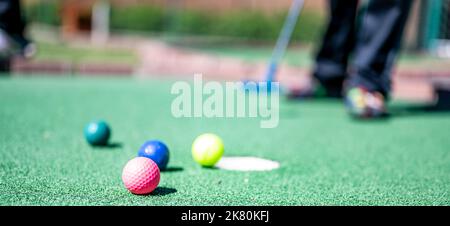 Minigolf-Spiel mit mehreren farbigen Kugeln in der Art eines Putter aufgereiht. Stockfoto