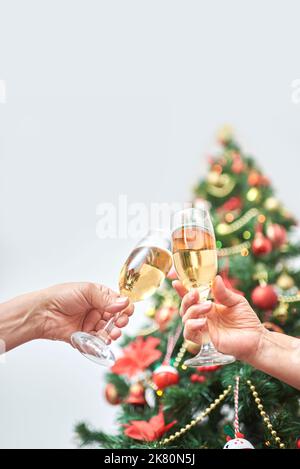 Unbekannte Erwachsene Paar Toasting während Weihnachten oder Neujahr, feiern Feiertage zusammen. Low-Angle-Ansicht einer weiblichen und männlichen Hand, die ein Paar anklirren Stockfoto