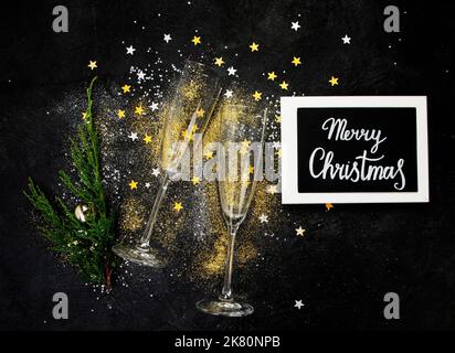 Zwei Sektgläser. Weihnachtsdekoration auf schwarzem Hintergrund. Frohes Neues Jahr. Draufsicht. Stockfoto