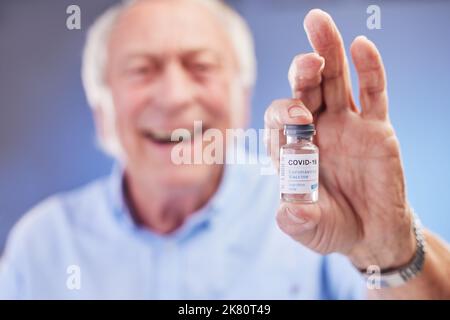 Es ist nie zu spät, um den Jab zu bekommen. Studioaufnahme eines Leiters, der vor blauem Hintergrund eine mit dem COovid-19-Impfstoff gefüllte Ampulle hält. Stockfoto