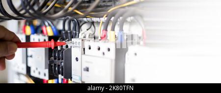 Elektriker Ingenieur Arbeitstester zur Messung der Spannung und des Stroms der elektrischen Stromleitung in der elektrischen Schaltschranksteuerung. Stockfoto