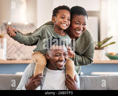 Die Welt braucht mehr kostbare Momente wie diese. Eine glückliche junge Familie spielt zu Hause auf dem Sofa zusammen. Stockfoto