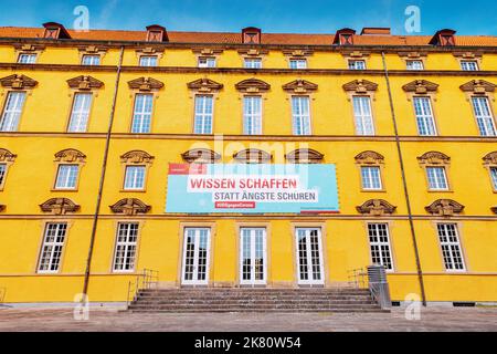 24. Juli 2022, Osnabrück, Deutschland: Die Inschrift auf dem Banner der Universität, dass das Wissen über das Coronavirus hilft, mit dem umzugehen Stockfoto