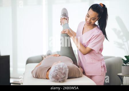 Das Geschenk der Apathie. Eine ältere Frau macht leichte Übungen während einer Sitzung mit einem Physiotherapeuten im Inneren. Stockfoto