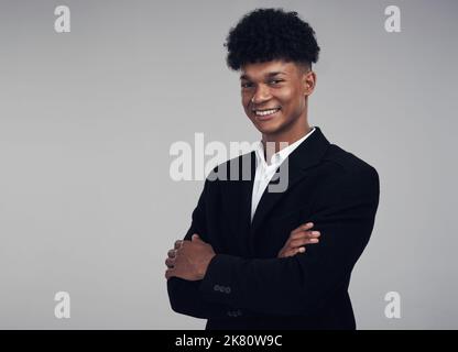 Vertrauen hält Sie aufrecht. Studioportrait eines selbstbewussten jungen Geschäftsmannes, der vor grauem Hintergrund posiert. Stockfoto