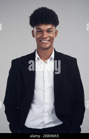 Ich gab alles und brachte mich weit. Studioportrait eines selbstbewussten jungen Geschäftsmannes, der vor grauem Hintergrund posiert. Stockfoto