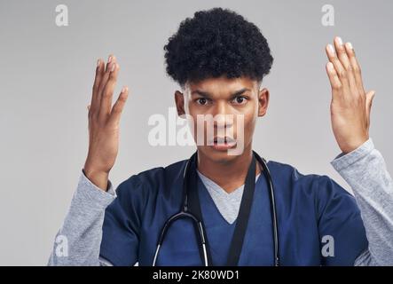 Was geschah mit den Anweisungen Ihrer Ärzte. Eine Krankenschwester, die verwirrt aussahen, während sie vor einem grauen Hintergrund stand. Stockfoto