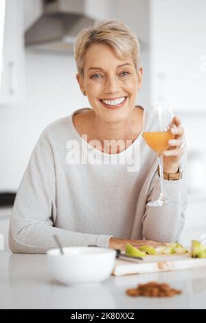 Dieser Saft ist erstaunlich. Eine Frau hält ein Glas Saft in ihrer Küche. Stockfoto