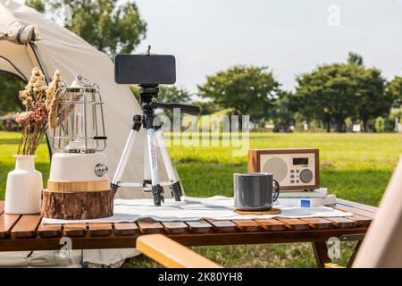 Camping Mood Aesthetics Smartphone mit Kaffee trinken Stockfoto