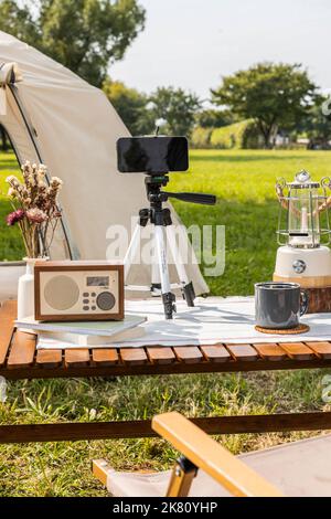 Camping Mood Aesthetics Smartphone mit Kaffee trinken Stockfoto