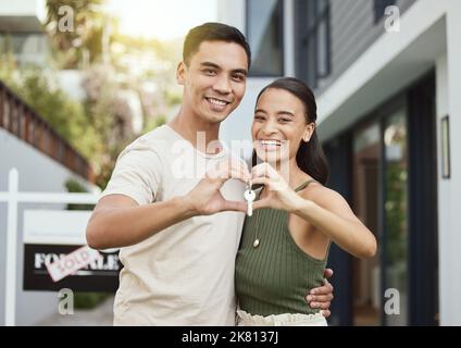 Ein junges Paar, das den Schlüssel zu ihrem neuen Zuhause in der Hand hielt, war froh, dies als unser Zuhause zu bezeichnen. Stockfoto