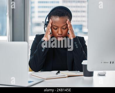 Die Zeit zum Entspannen ist, wenn Sie keine Zeit dafür haben. Eine junge Frau, die sich gestresst fühlt, während sie ein Headset und einen Computer spät in der Nacht in einem modernen verwendet Stockfoto