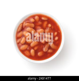 Draufsicht auf gebackene weiße Bohnen mit Tomatensauce in Keramikschale isoliert auf Weiß Stockfoto