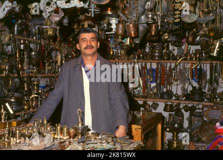 Syrien: Ein Anbieter von Messing- und Metallwaren im alten Großen Basar in Aleppo (1997). Der große Basar von Aleppo (auf Arabisch, suq oder suq) wurde zuerst von den ägyptischen Mamelukes, die die Mongolen vertrieben hatten, und dann, nach 1516, von den Türken, die Aleppo in das Osmanische Reich eingliederte, wieder aufgebaut. Während des syrischen Bürgerkrieges, der 2011 begann, erlitten die historischen Suqs von Aleppo schwere Schäden. Aleppo, die zweite Stadt Syriens, ist wahrscheinlich die längste kontinuierlich bewohnte Siedlung der Welt. Sein arabischer Name, Halab, wird in semitischen Texten des dritten Jahrtausends v. Chr. erwähnt. Stockfoto