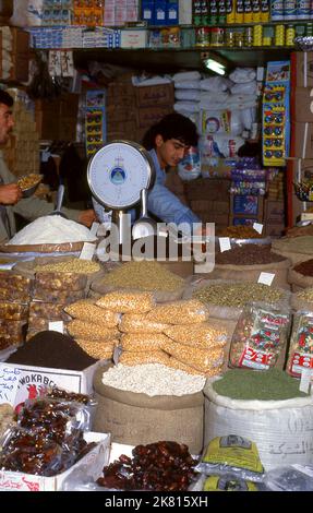 Syrien: Ein allgemeiner Trockenwarenhändler im alten Großen Basar in Aleppo (1997). Der große Basar von Aleppo (auf Arabisch, suq oder suq) wurde zuerst von den ägyptischen Mamelukes, die die Mongolen vertrieben hatten, und dann, nach 1516, von den Türken, die Aleppo in das Osmanische Reich eingliederte, wieder aufgebaut. Während des syrischen Bürgerkrieges, der 2011 begann, erlitten die historischen Suqs von Aleppo schwere Schäden. Aleppo, die zweite Stadt Syriens, ist wahrscheinlich die längste kontinuierlich bewohnte Siedlung der Welt. Sein arabischer Name, Halab, wird in semitischen Texten des dritten Jahrtausends v. Chr. erwähnt. Stockfoto