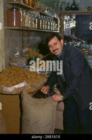 Syrien: Verkauf von Nüssen und getrockneten Früchten im alten Großen Basar in Aleppo (1997). Der große Basar von Aleppo (auf Arabisch, suq oder suq) wurde zuerst von den ägyptischen Mamelukes, die die Mongolen vertrieben hatten, und dann, nach 1516, von den Türken, die Aleppo in das Osmanische Reich eingliederte, wieder aufgebaut. Während des syrischen Bürgerkrieges, der 2011 begann, erlitten die historischen Suqs von Aleppo schwere Schäden. Aleppo, die zweite Stadt Syriens, ist wahrscheinlich die längste kontinuierlich bewohnte Siedlung der Welt. Sein arabischer Name, Halab, wird in semitischen Texten des dritten Jahrtausends v. Chr. erwähnt. Stockfoto