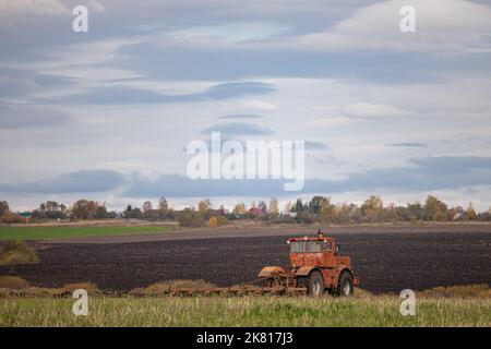 Große alte Modell Traktor pflügt den Boden. Landwirt pflügt das Land. Traktor arbeitet auf dem Feld. Hochwertige Fotos Stockfoto