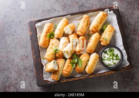 borek sigara Boregi gebratenes Gebäck in Käse in Phyllo closeup auf dem Holzbrett auf dem Tisch eingewickelt. Horizontale Draufsicht von oben Stockfoto