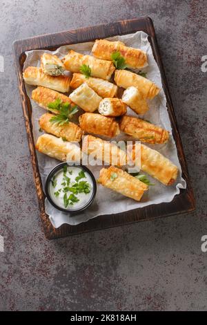 Sigara Boregi Türkische Zigarrenrollen gefüllt mit Käse und Kräutern Nahaufnahme auf dem Holzbrett auf dem Tisch. Vertikale Draufsicht von oben Stockfoto