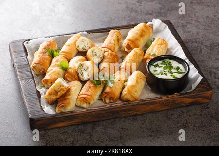 borek sigara Boregi gebratenes Gebäck in Käse in Phyllo closeup auf dem Holzbrett auf dem Tisch eingewickelt. Horizontal Stockfoto