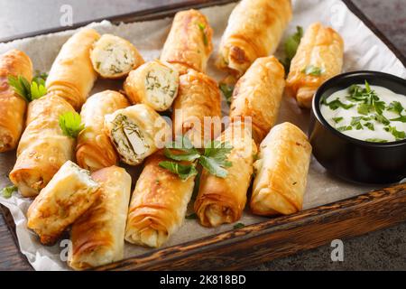 Sigara Boregi Türkische Snacks aus Phyllo-Gebäck, gefüllt mit Feta-Käse aus der Nähe auf dem Holzbrett auf dem Tisch. Horizontal Stockfoto