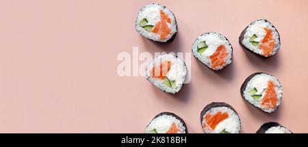 Banner frische Sushi-Rollen mit Lachs auf rosa Hintergrund von oben. Blick von oben auf die japanische Küche Stockfoto