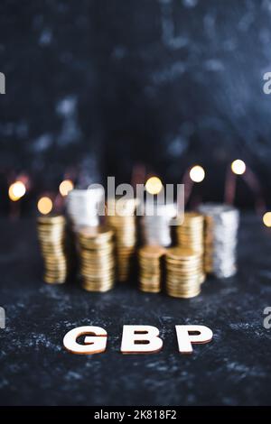 Währungskurskonzeptuelles Bild, britisches Pfund Sterling Text vor Münzstapeln Symbol der Performance an den globalen Aktienmärkten Stockfoto