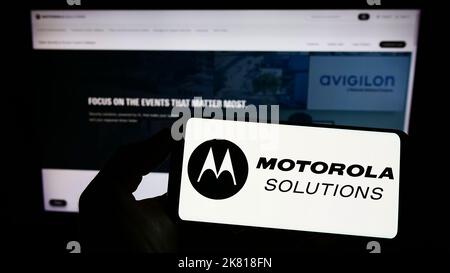 Person, die ein Mobiltelefon mit dem Logo des amerikanischen Unternehmens Motorola Solutions Inc. Auf dem Bildschirm vor der Unternehmenswebseite hält. Konzentrieren Sie sich auf die Telefonanzeige. Stockfoto