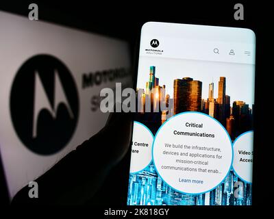 Person, die Mobiltelefon mit der Webseite des US-Unternehmens Motorola Solutions Inc. Auf dem Bildschirm vor dem Unternehmenslogo hält. Konzentrieren Sie sich auf die Mitte des Telefondisplays. Stockfoto